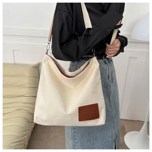 Detalle del bolso tote de lona con parche de cuero y correa de hombro ancha texturizada