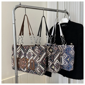 Detail of ethnic woven tote bags with geometric patterns and metal chain leather handles
