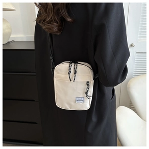 Petit sac bandoulière crème avec zips noirs porté par un mannequin en intérieur chic