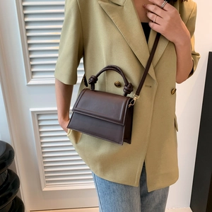 Petit sac à bandoulière marron foncé avec poignée nouée porté par un mannequin