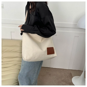 Detalle del bolso tote grande de lona crema con etiqueta de cuero sintético marrón