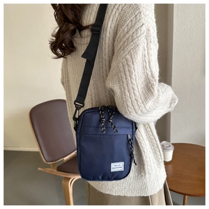 Détail de la bandoulière en nylon bleu marine avec écusson HELLO WEEKEND et sangle