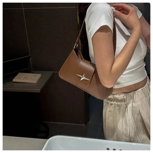 Dettaglio della borsa baguette in pelle marrone con fibbia metallica a forma di stella