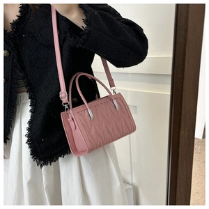 Detail of pink quilted crossbody bag with top handle and silver metal hardware