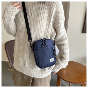 Close-up of Navy nylon square crossbody bag featuring HELLO WEEKEND text and zipper detail