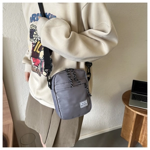 Detail showing grey oxford fabric shoulder bag with Hello Weekend label in indoor setting