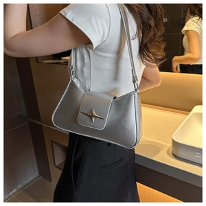 Sac sous le bras argenté avec étoile Y2K porté par un mannequin en décor moderne