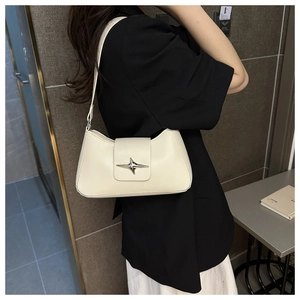 Dettaglio della borsa hobo crema con stella argentata su modella con blazer nero