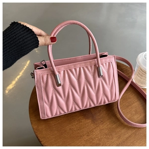 Detail of pink quilted handbag with wavy stitching pattern and silver metal hardware