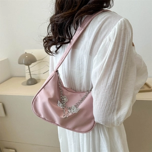Sac à bandoulière rose minimaliste avec chaîne argentée et breloques papillons sur modèle