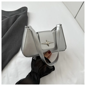 Détail d'un sac à bandoulière argenté avec finition métallisée et emblème étoile en métal