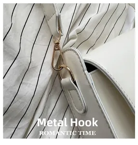 Detailed close-up of premium golden hardware hook on a white leather shoulder handbag