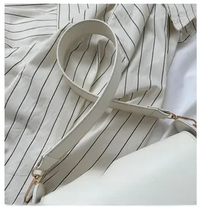 Detail of white PU leather bag showing wide strap with gold D-ring and lobster clasp