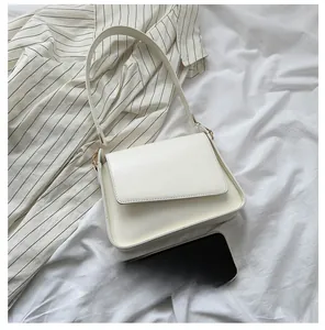 Detailed view of cream minimalist crossbody bag next to smartphone for scale comparison
