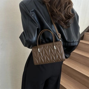 Dark brown quilted crossbody bag with textured waves and silver hardware for women