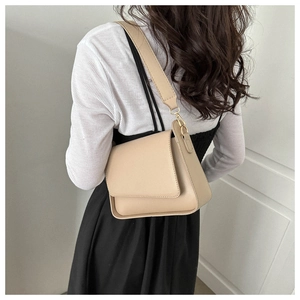 Rear view of minimalist beige crossbody bag with wide strap on woman shoulder