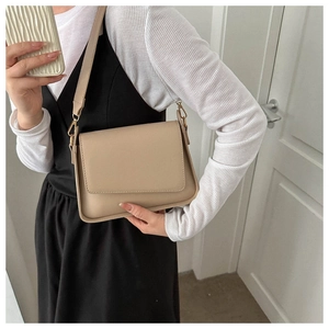 Detail of minimalist beige faux leather crossbody bag with adjustable shoulder strap