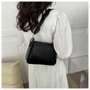 Borsa a tracolla minimalista in pelle nera con tracolla larga indossata da modella