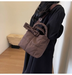 Brown quilted tote bag with bow detail shown on model in a minimalist setting