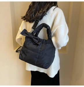 Close-up of black quilted puffer tote bag with a large bow detail and padded handles