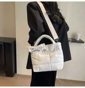 Detailed shot of white quilted tote bag featuring a large decorative bow and wide strap