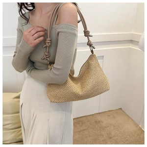 Dettaglio borsa a tracolla intrecciata beige con spalline annodate e finiture metalliche