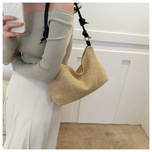 Dettaglio borsa a spalla in paglia intrecciata beige con sottili spalline in pelle nera