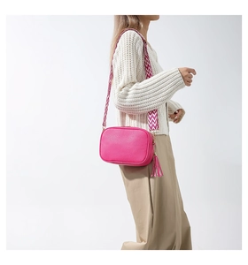 Detail of rose pink crossbody bag with geometric shoulder strap and leather fringe tassel