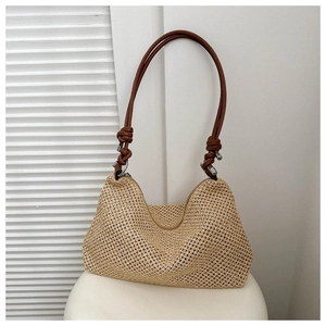 Dettaglio di borsa tote intrecciata beige con tracolla in pelle marrone e nodo decorativo