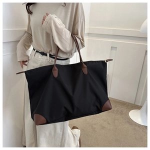 Modelo con bolso tote de nailon negro con asas de cuero marrón en un interior moderno