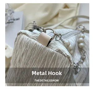 Detail of white pleated barrel bag with silver hardware hooks and pearl chain accents