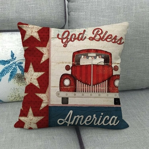 Close-up of linen pillow cover with red truck and God Bless America print on grey sofa