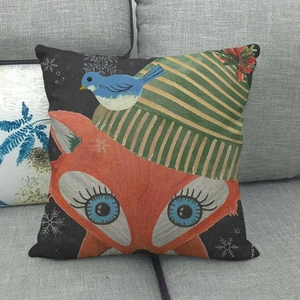 Close-up of a linen Christmas pillow cover with an orange fox and winter snowflakes