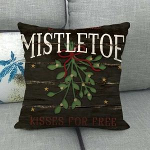 Detail showing vintage wood grain texture and Mistletoe Kisses For Free print on festive pillow