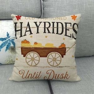 Detail of pumpkin hayrides harvest pillow cover on a gray sofa for autumn home decor