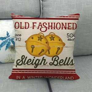 Vintage Christmas sleigh bells pillow cover on a gray sofa featuring rustic fabric texture