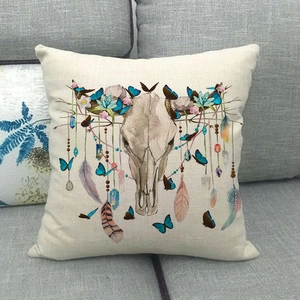 Dettaglio copricuscino in lino con teschio di mucca, fiori e piume stile etnico