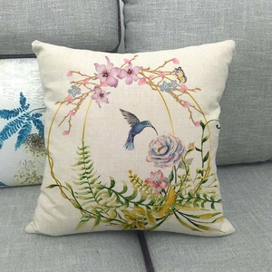 Fodera per cuscino in lino con ghirlanda floreale e colibrì su un divano grigio