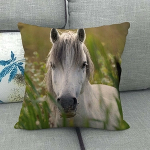 Detalle de un cojín cuadrado de lino con estampado realista de caballo blanco en sofá gris