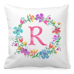 Macro shot of peach skin fabric cushion cover with floral wreath and letter R design