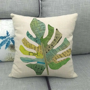 Federa per cuscino in lino con stampa a foglia di ananas su un divano grigio