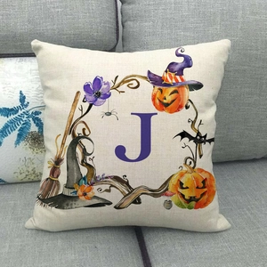 Dettaglio del cuscino di Halloween con zucca ad acquerello e lettera J su divano grigio