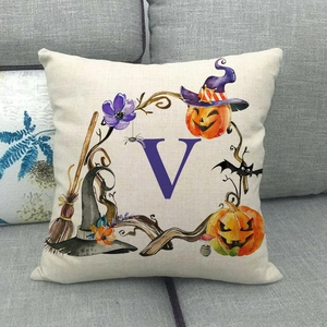 Dettaglio del copricuscino Halloween con lettera V e zucche su un divano grigio