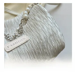 Detail of pleated fabric texture with pearl chain and metallic flower buckle on a handbag