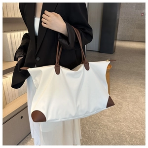 Detalle de bolso de viaje en nylon blanco con refuerzos de cuero marrón y gran tamaño