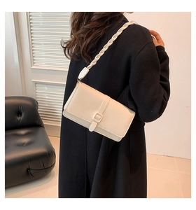 Dettaglio borsa a tracolla minimalista in similpelle crema con cinturino a treccia