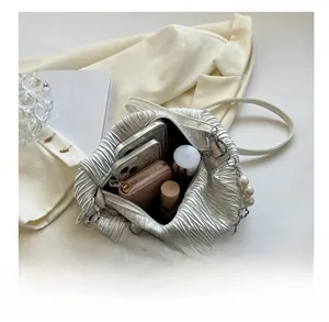 Detailed interior capacity of white ruched shoulder bag with pearl chain and daily items