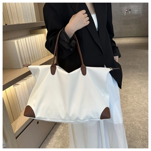 Detalle del bolso tote de nailon blanco con ribete de cuero marrón y cremallera dorada