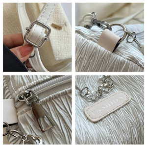 Detailed close-up of textured fabric crossbody bag with floral chain and silver zipper