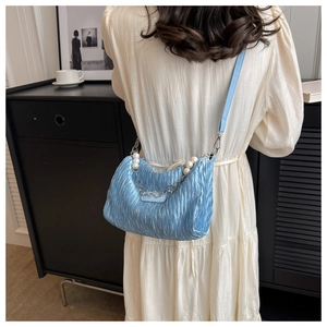Detail of light blue pleated cloud bag with pearl chain handle and leather strap on model